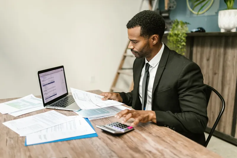 Comparing quotes on a laptop with printed documents and a calculator